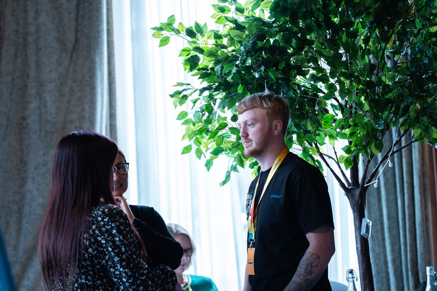 Delegates talking beside one of the trees in the room